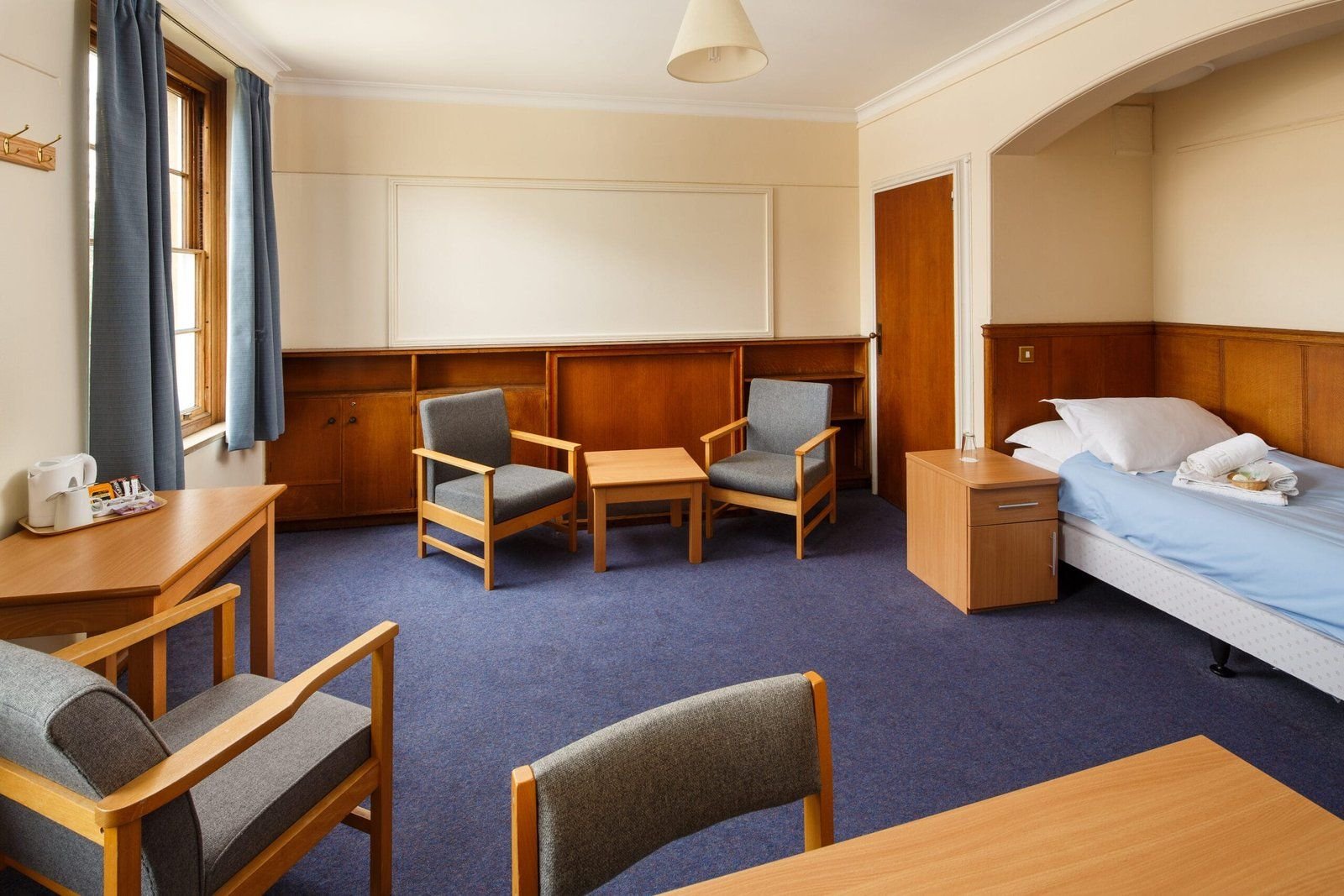 Single non-ensuite bedroom at Christ’s College, Cambridge, with wood panelling and a desk by the window.
