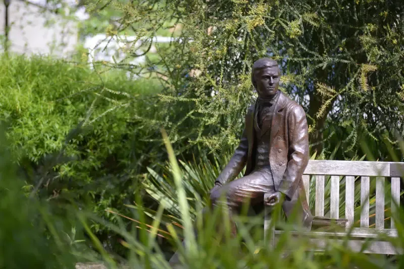 The Darwin Garden at Christ’s College, Cambridge, with colourful borders and the bronze statue of Charles Darwin on a bench.