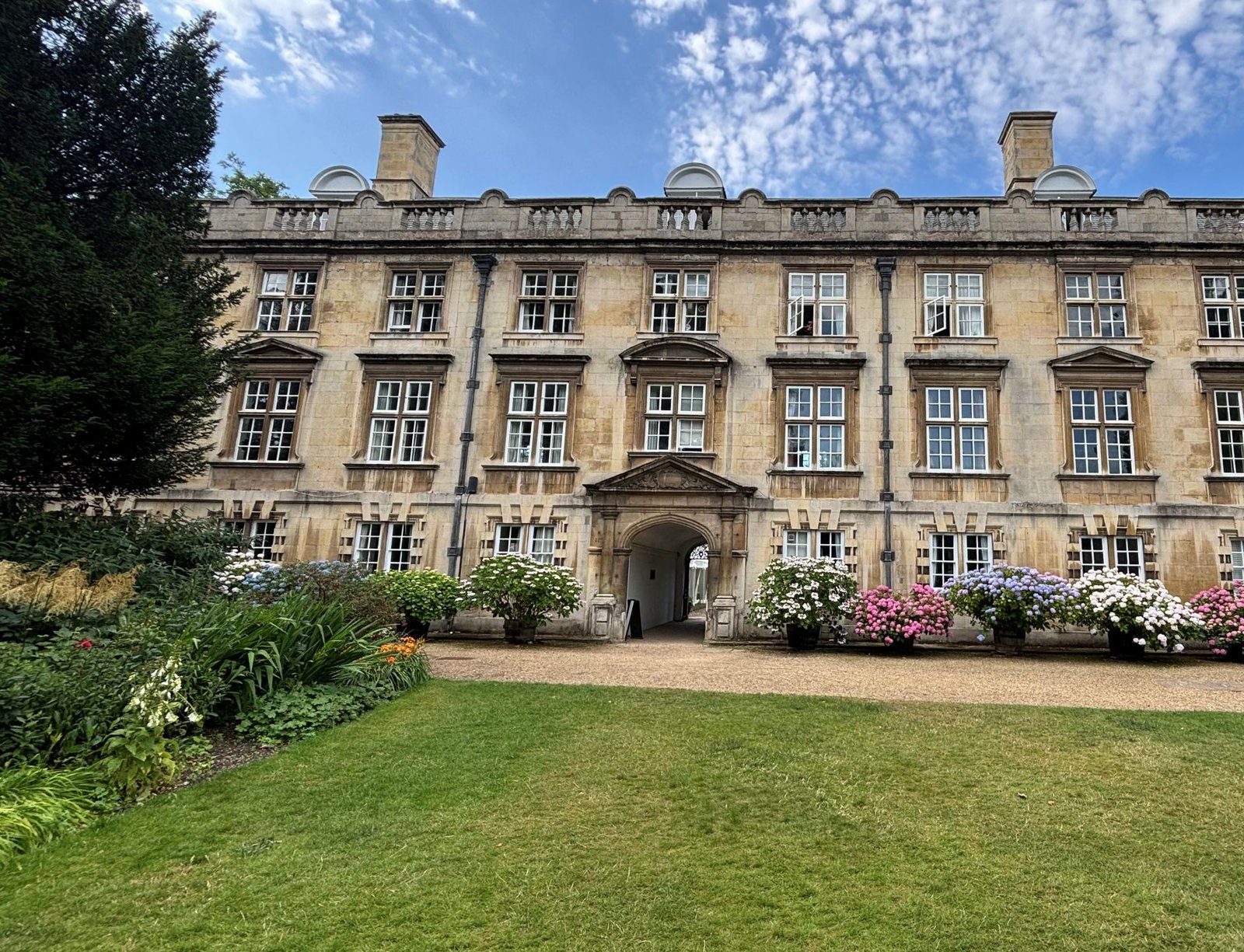 The Fellows' Building in the Fellows' Garden at Christ's College, with a border of pink, blue and cream hydrangeas.