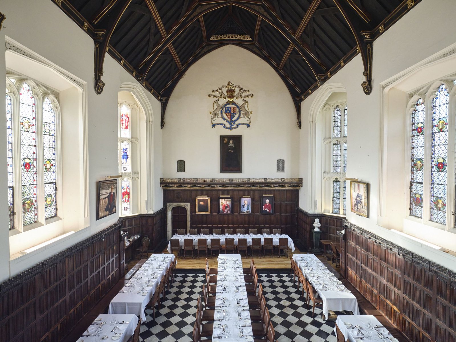 The Great Hall at Christ's College, Cambridge, set for an event with white tablecloths and cutlery laid out.