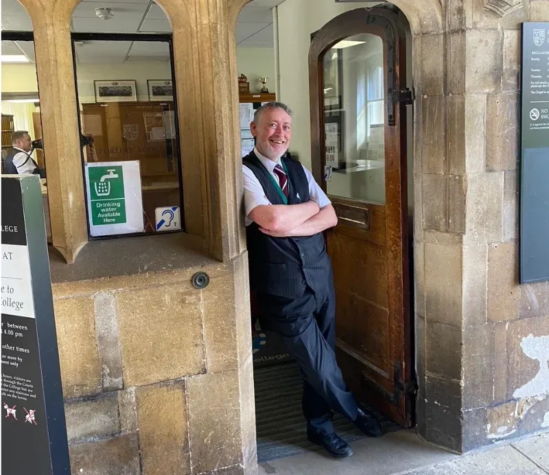 One of the Porters at Christ’s College, Cambridge, standing in the doorway of the Porters’ Lodge.