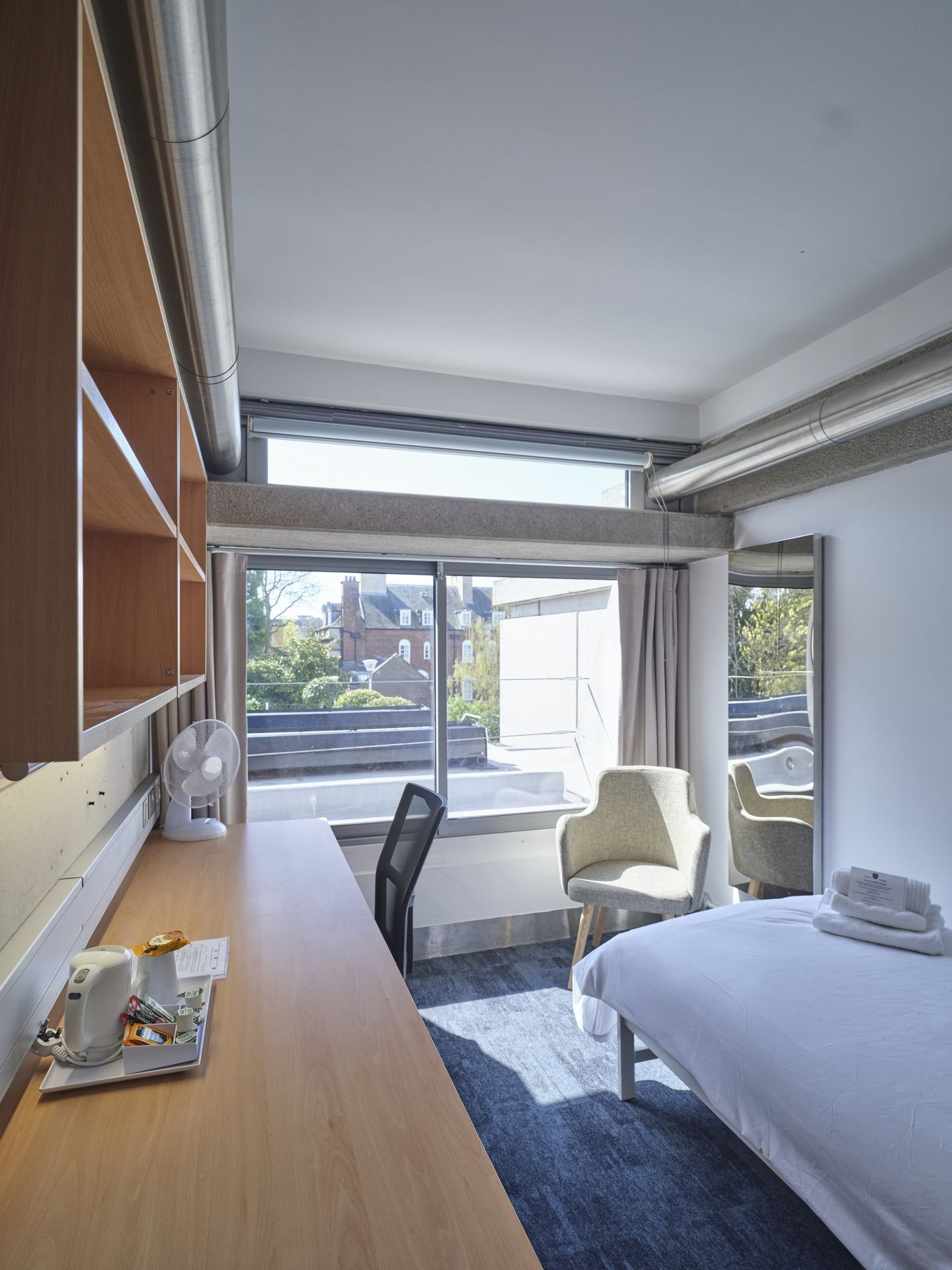 Single guest bedroom at Christ's College, Cambridge, with a desk beneath a large window.