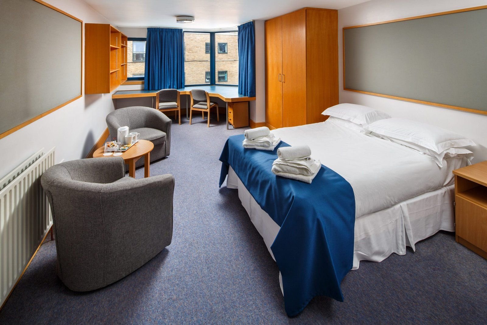 Double ensuite room at Christ’s College, Cambridge, with a double bed, armchairs and a desk.
