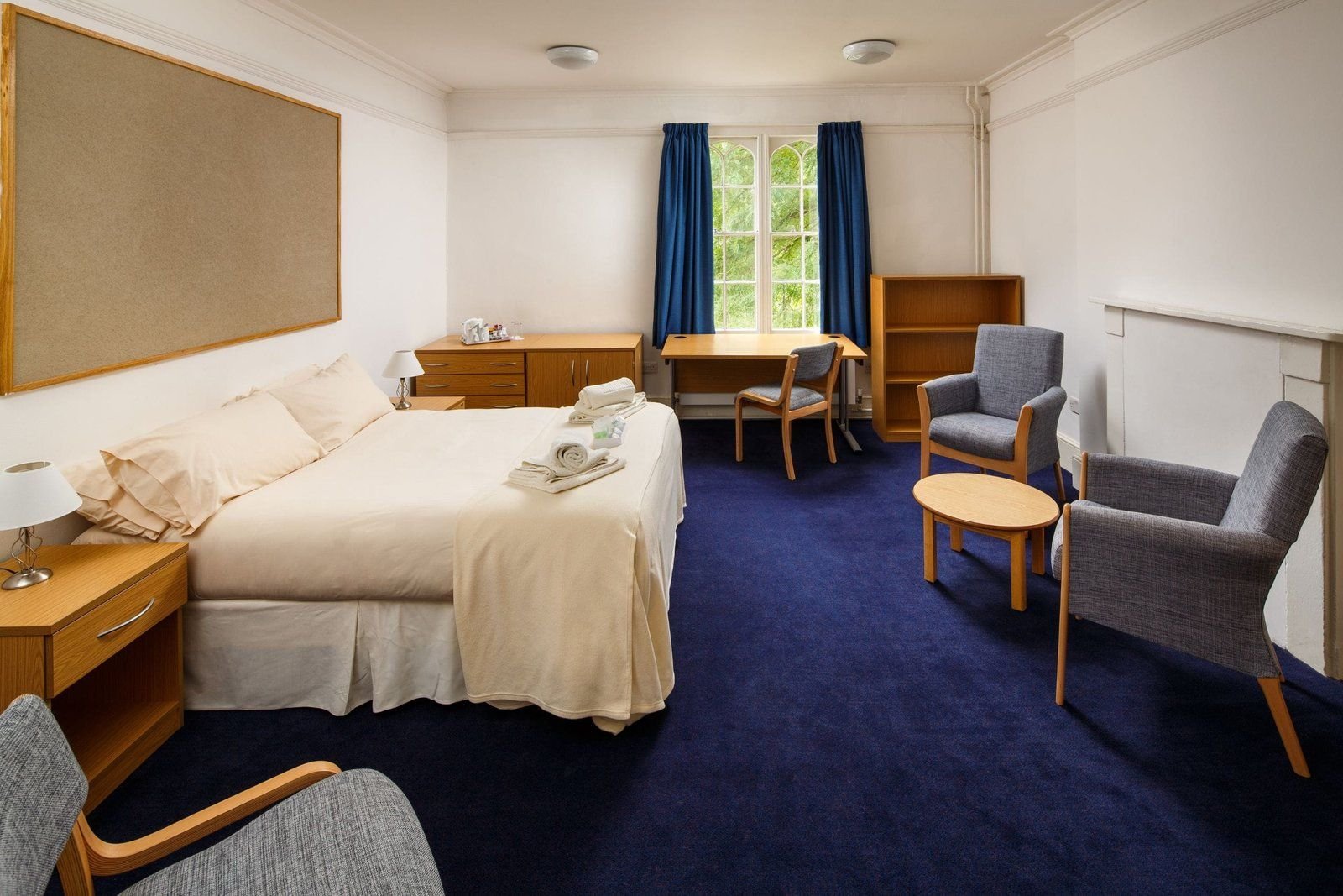 Superior double bedroom at Christ’s College, Cambridge, with a double bed, armchairs and a round table.