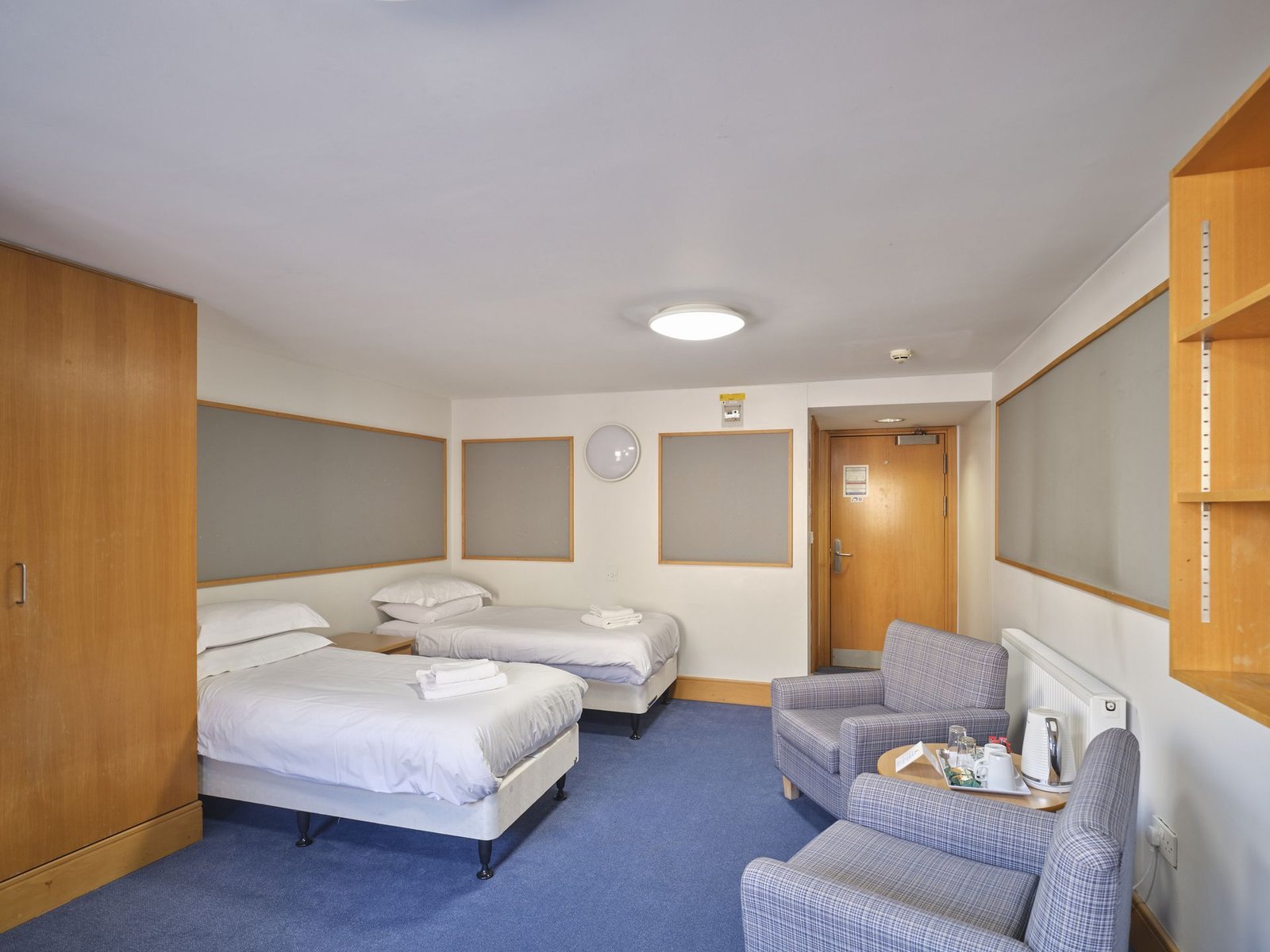 Twin ensuite guest room at Christ's College, Cambridge, with armchairs and a coffee table.