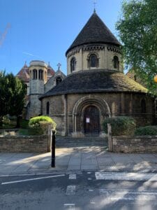 Exterior view of the Round Church in Cambridge, a distinctive Norman-style building with a circular nave and stone facade, set against a bright sky. An great place to visit during a weekend in Cambridge.