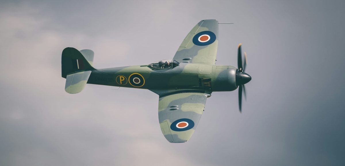 WWII airfields around Cambridge: paul-jespers-HKqLX9NTtKc-unsplash WWII airfields around Cambridge: A wartime plane flying in the sky.